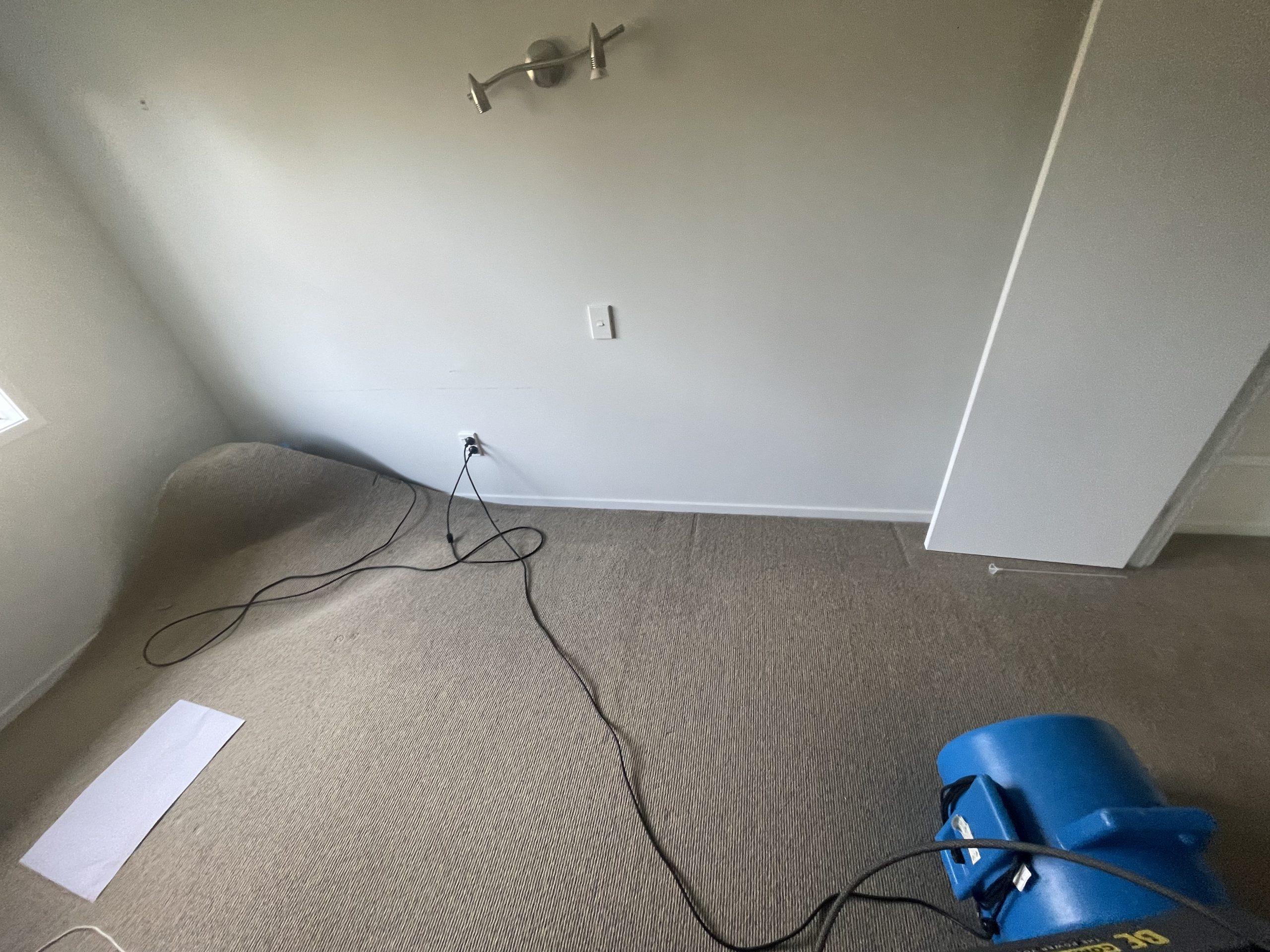 Air mover set up in the bedroom carpeted area during controlled drying