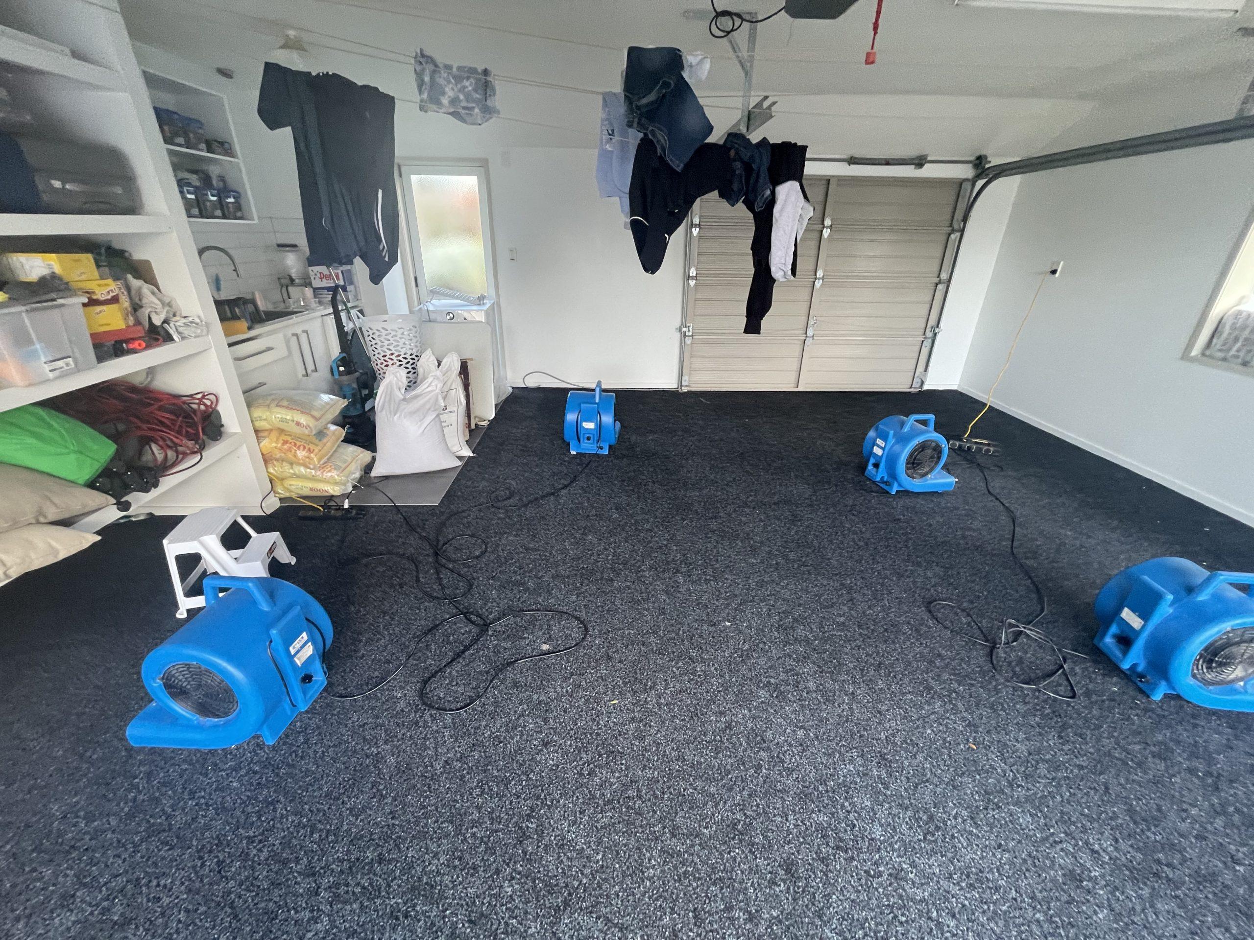 Air movers positioned in the garage during controlled drying after the documented washing-machine leak