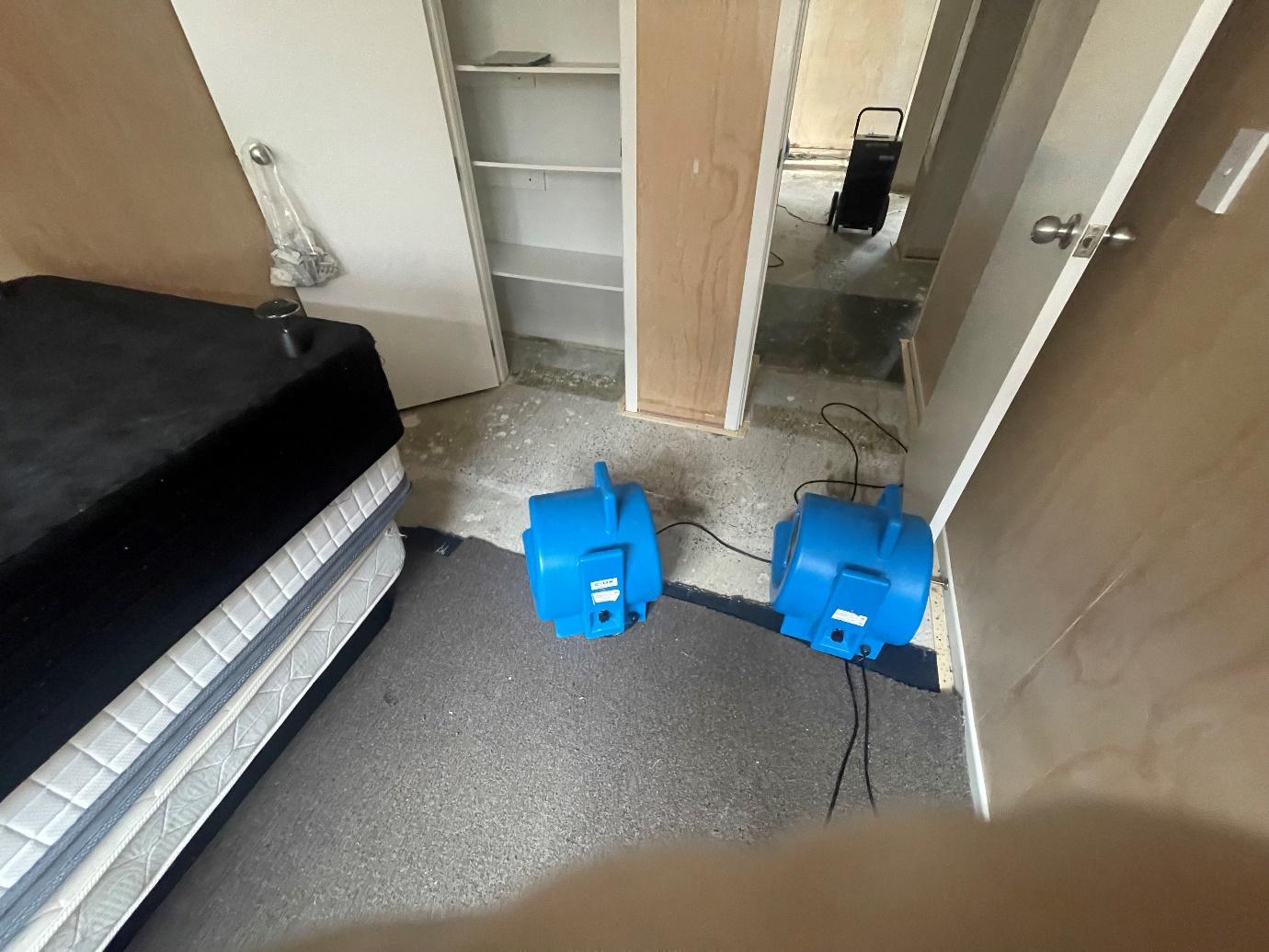 Air movers positioned in an affected bedroom for structural drying